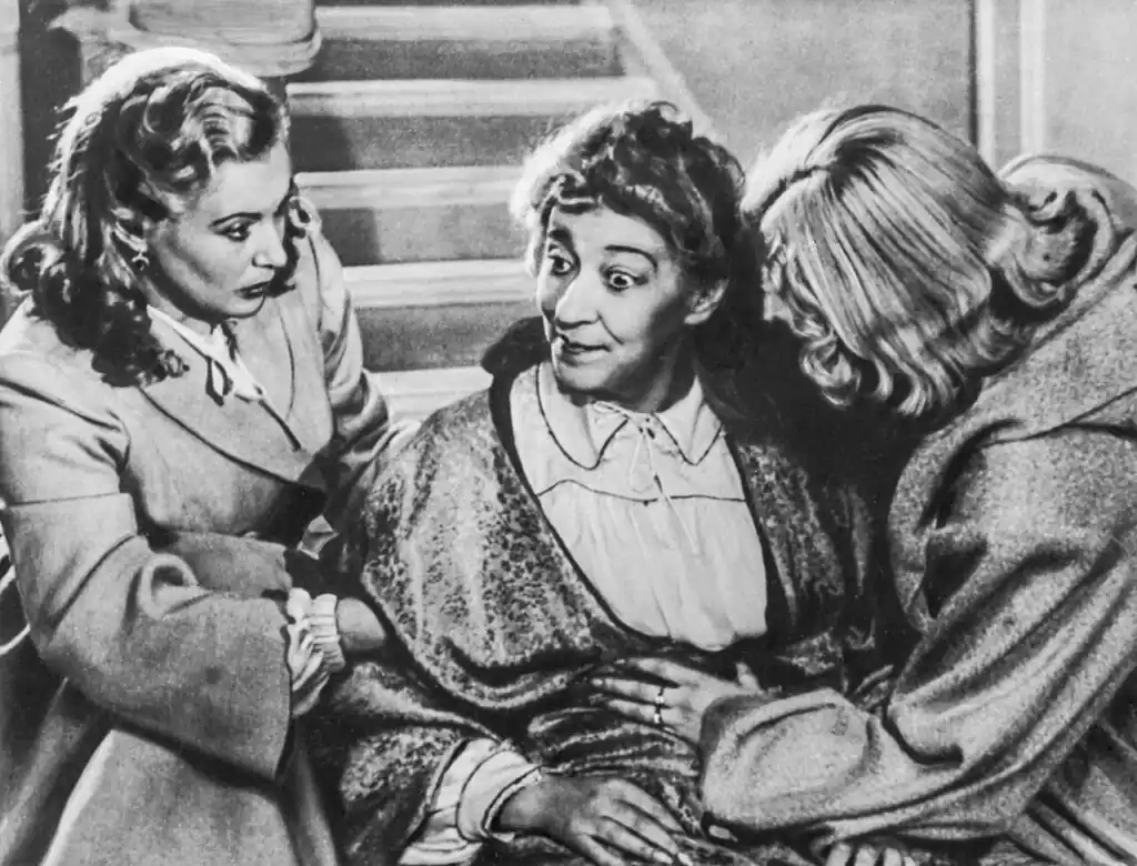 Три женщины на лестнице: в центре Фаина Раневская с удивлённым лицом, по бокам к ней прижались две молодые женщины в пальто